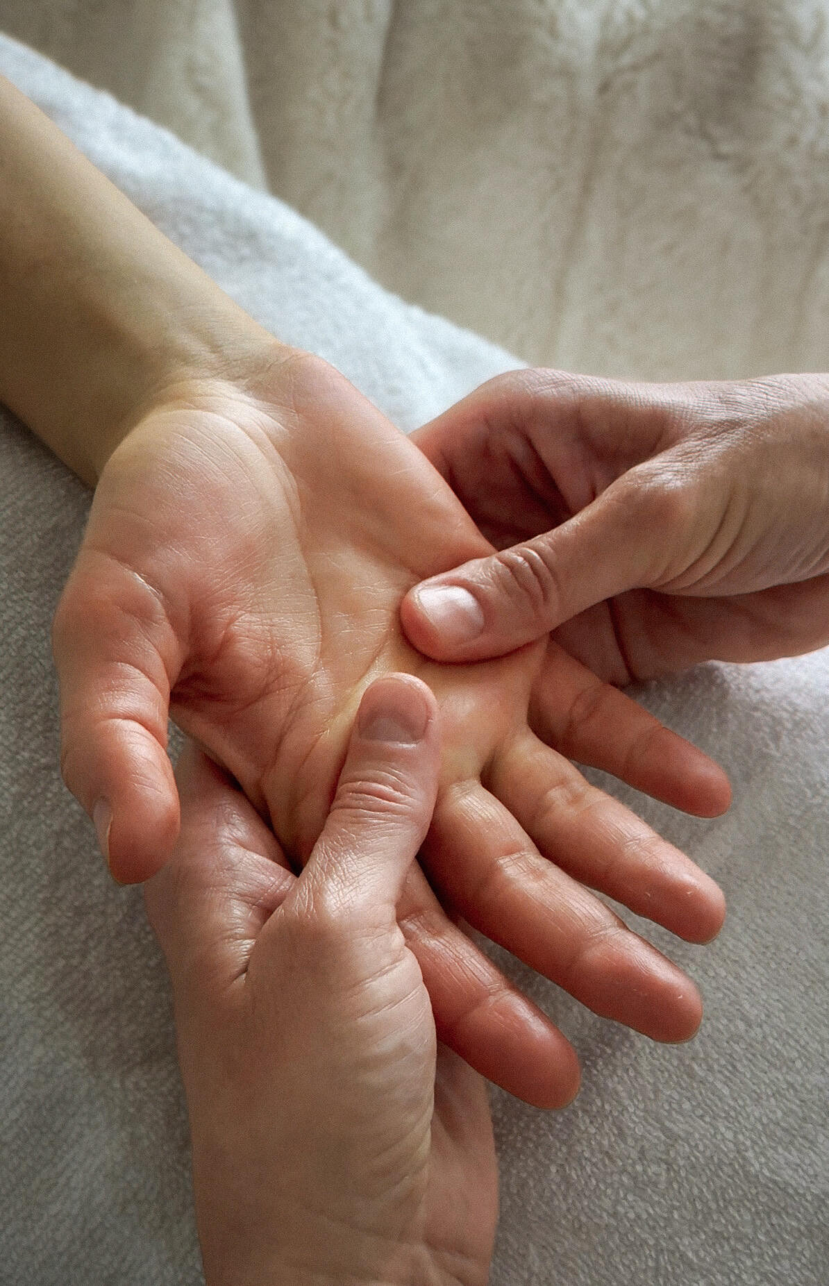 Hand reflexology Calgary Person lying on table receiving a hand reflexology treatment. Reflexologists hands are visible