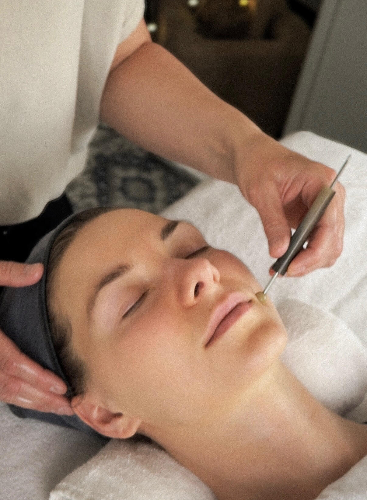Facial reflexology Person lying on table receiving a facial reflexology treatment. Reflexologists hands are visible and using a Dien Chan tool to press on a reflex point.